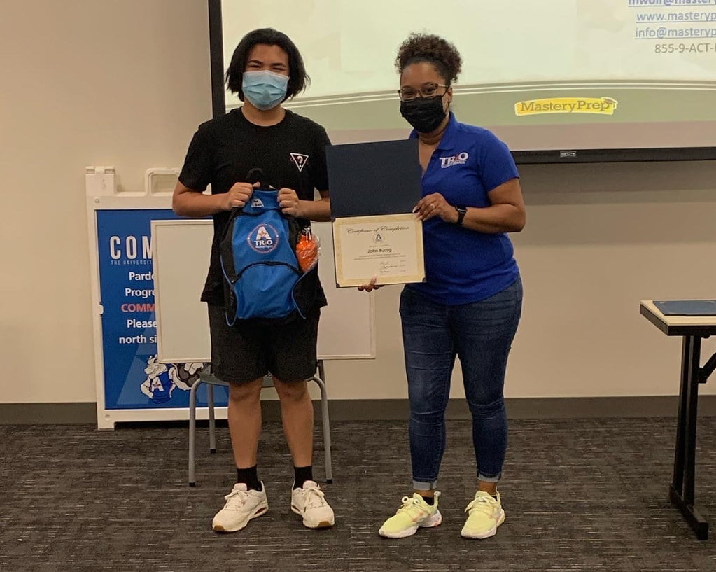 student and staff person holding and award