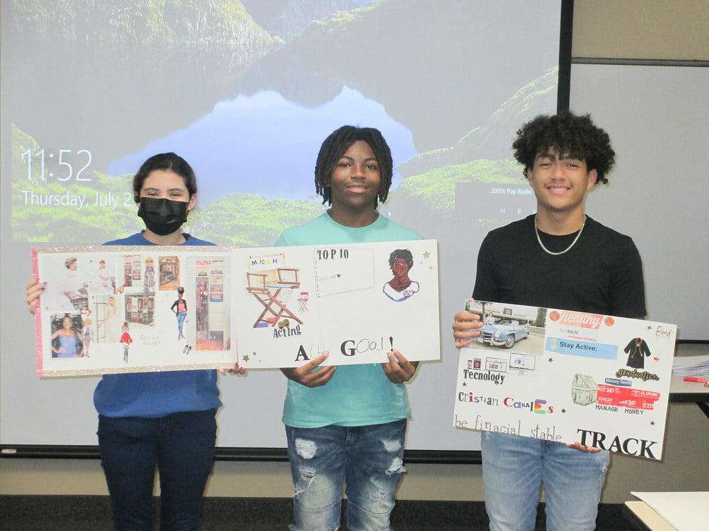 three students showing their art work posters