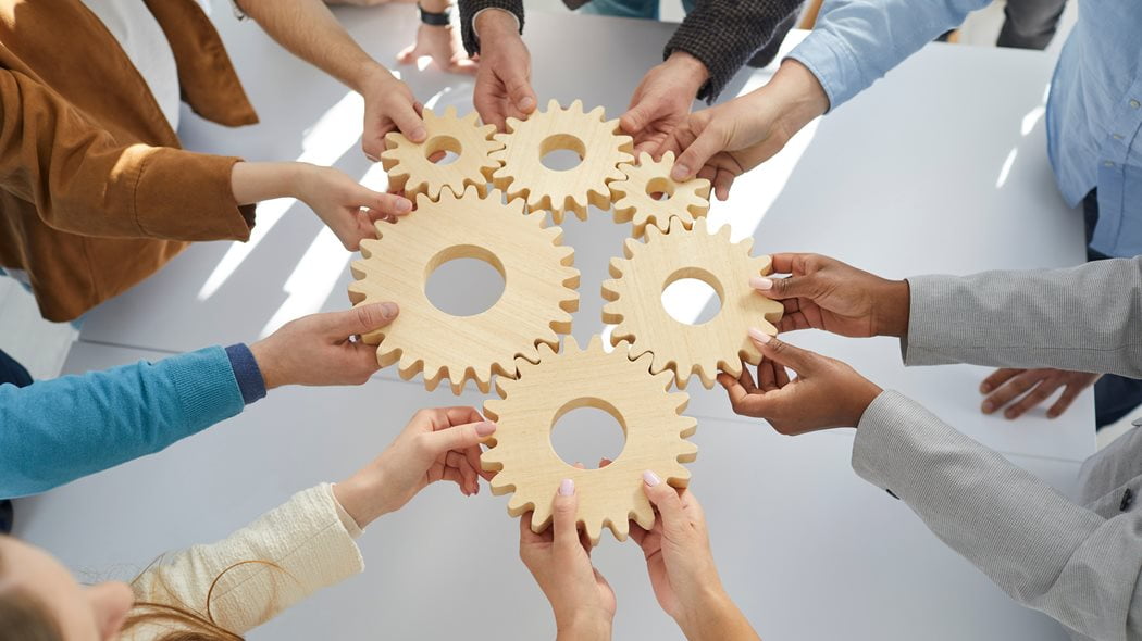 employees holding wooden cogs together