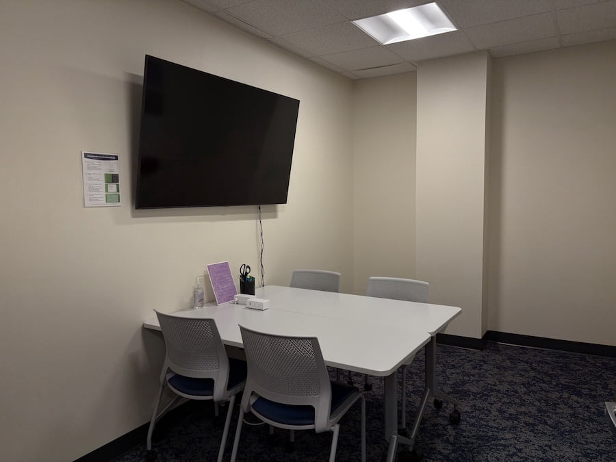 room with a tv on the wall and a table with chairs