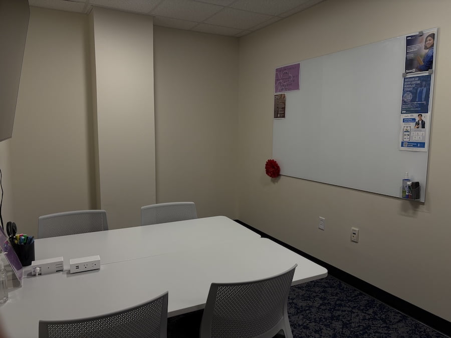room with a white board on the wall and a table with chairs