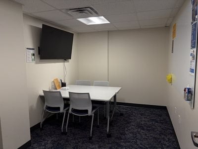 room with a tv on the wall and a table with chairs