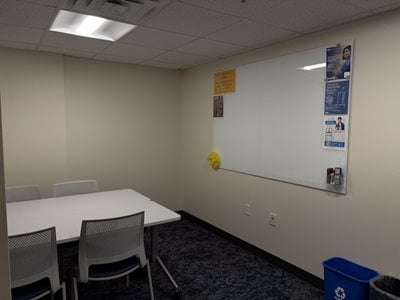 room with a white board on the wall and a table with chairs
