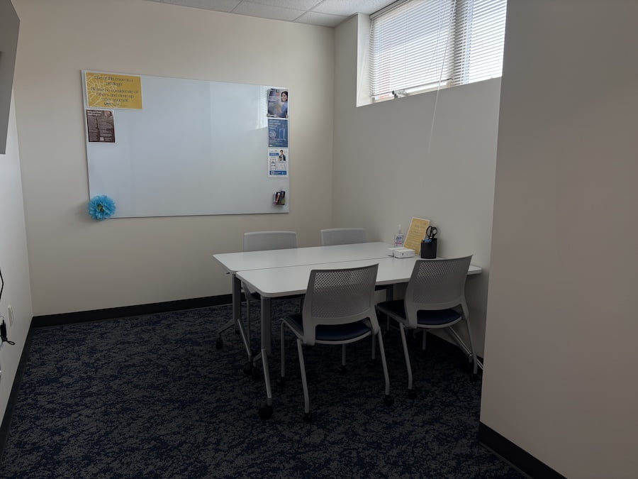 room with a white board on the wall, and a table with chairs