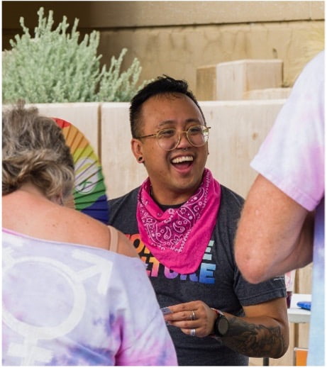 person smiling with a black shirt and pink scarf