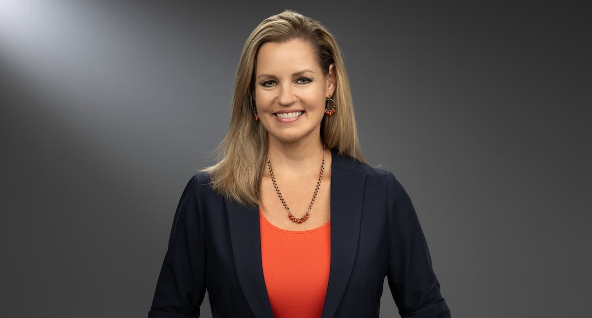 image of marie schultz - a woman wearing a black blazer jacket and orange top