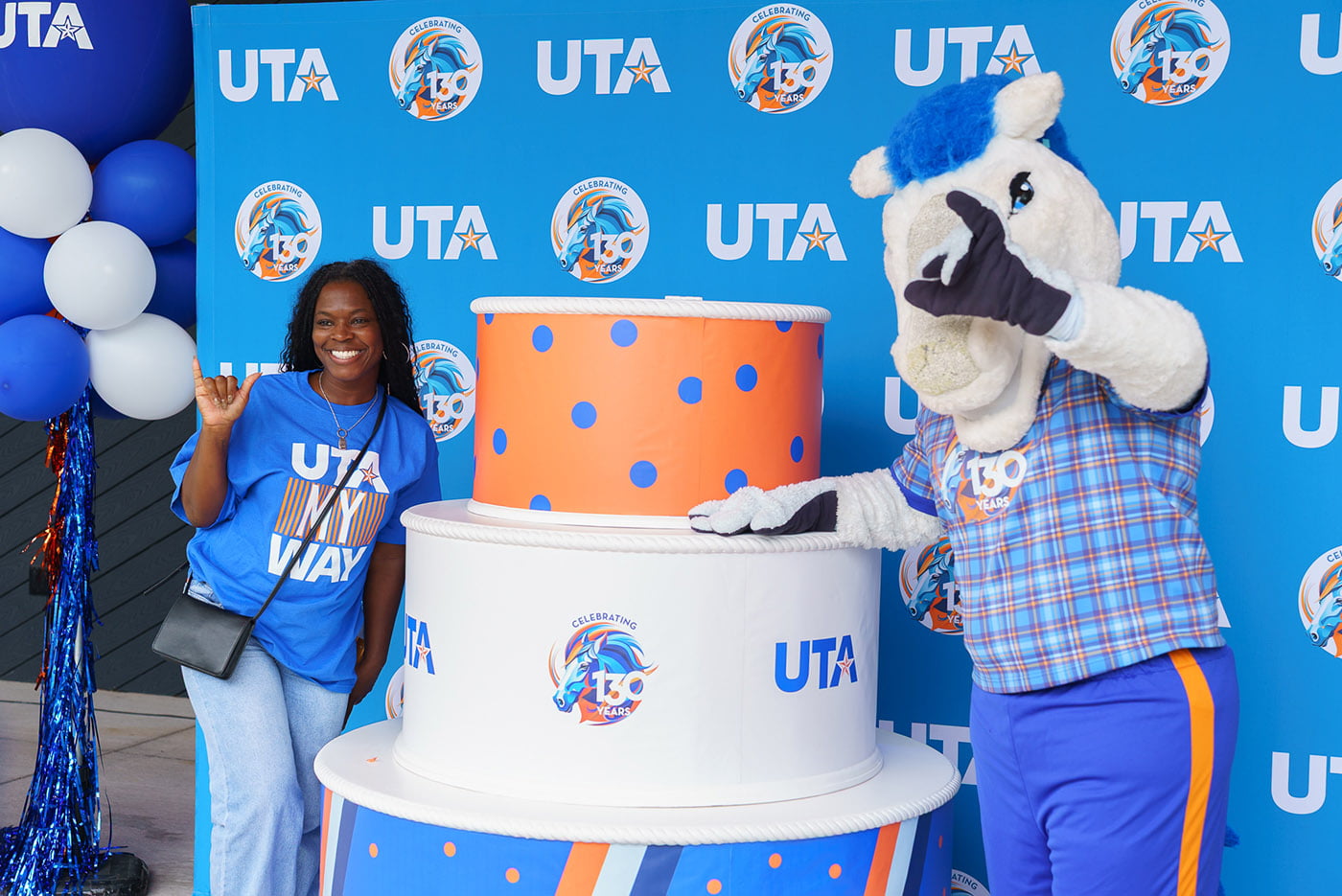 blaze and a student posing with uta's 130 anniversary birthday cake