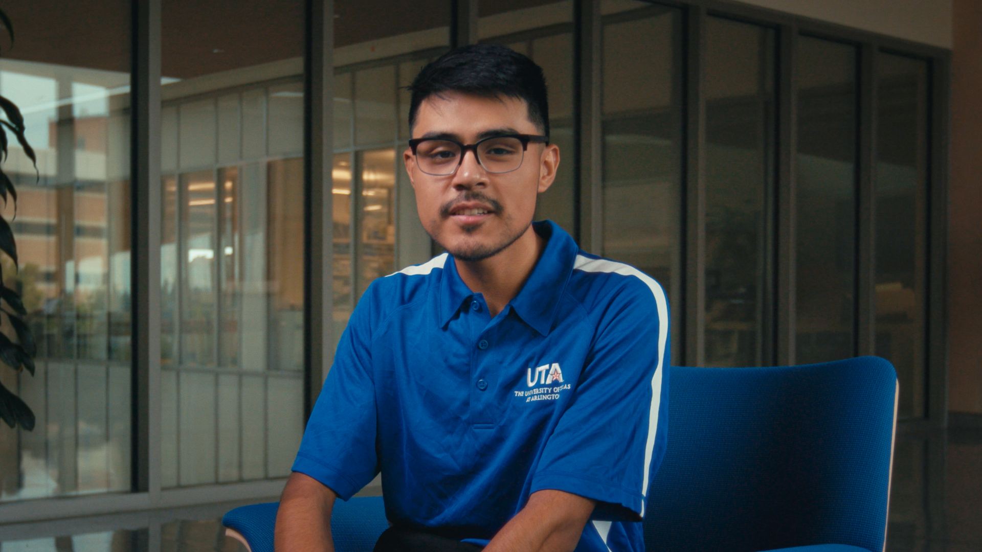 A student sitting in a chair wearing a blue polo shirt