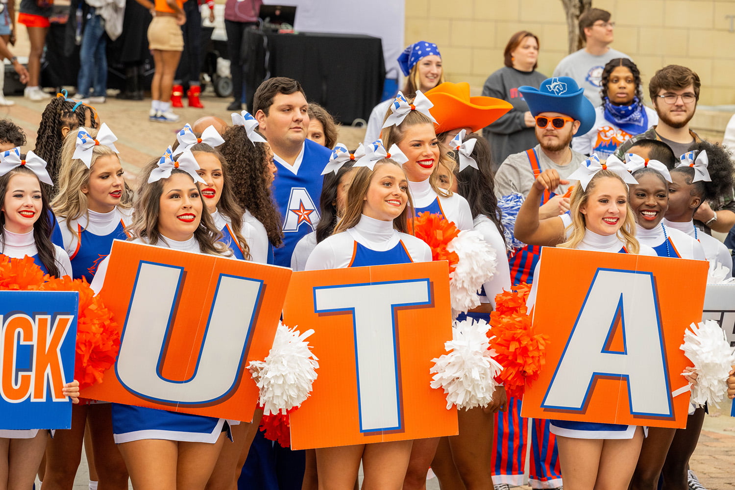 cheerleaders holding three signs that say u t a