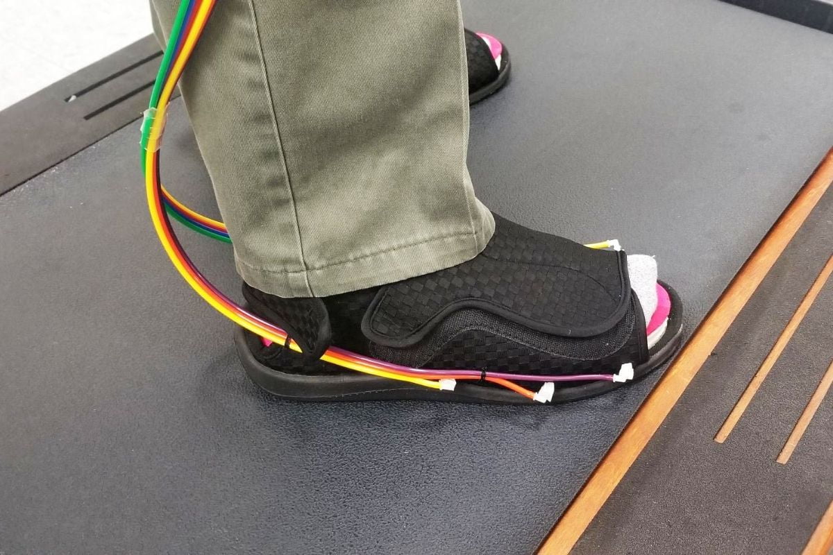 A researcher demonstrates the dual-layer insole apparatus." _languageinserted="true