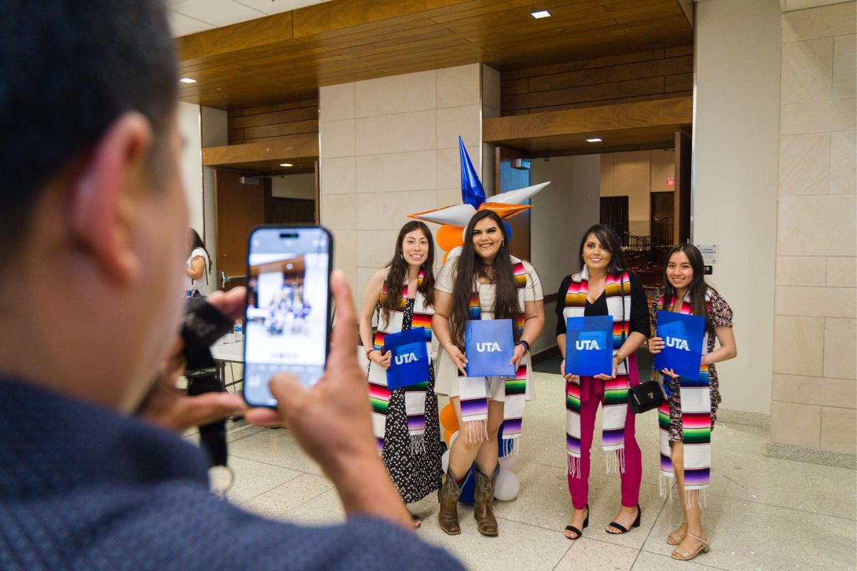 Four UTA students posing at Celebrando el Exito, getting their photo taken