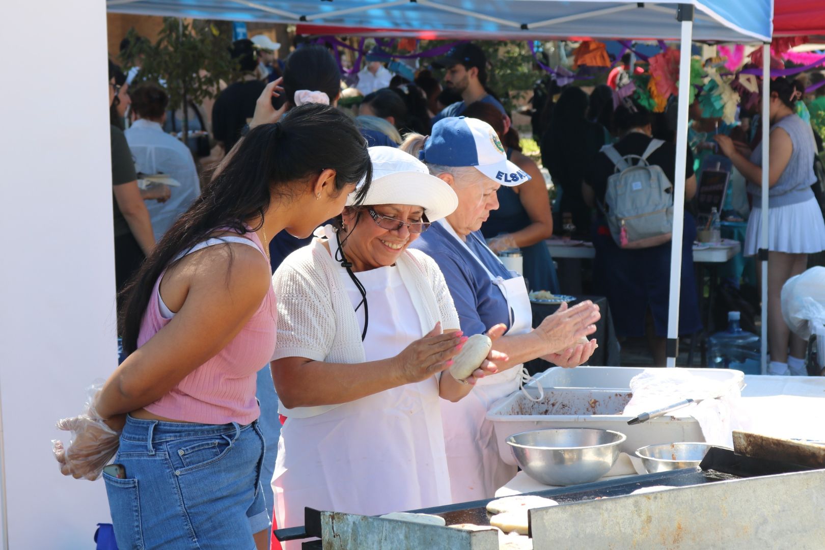 Image shows people making pupusas, a Salvadoran dish, at UTA's Park(ing) Day