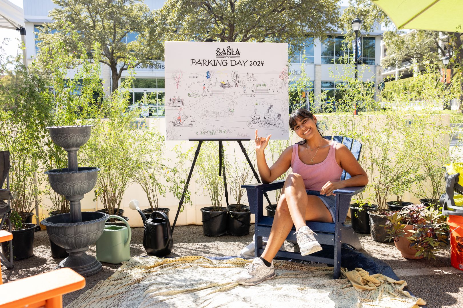 Image shows architecture student Gabriela Gonzalez posing with the Park(ing) Day sign