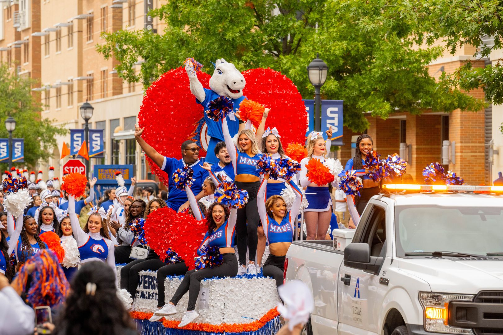 Image shows UTA students dressed in blue and orange on a parade float during Homecoming 2023 