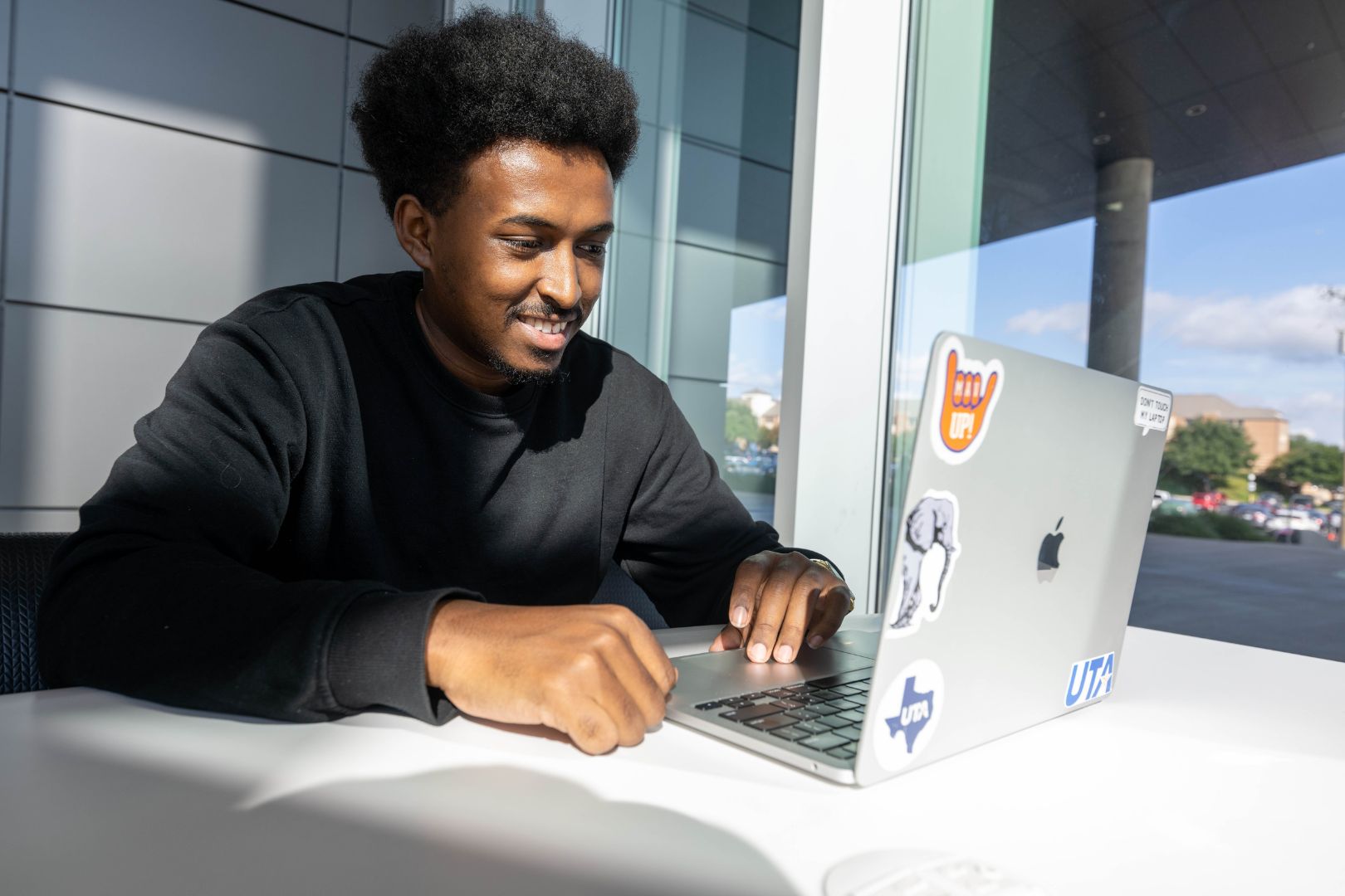 Image shows a UTA student taking an online course on his laptop 
