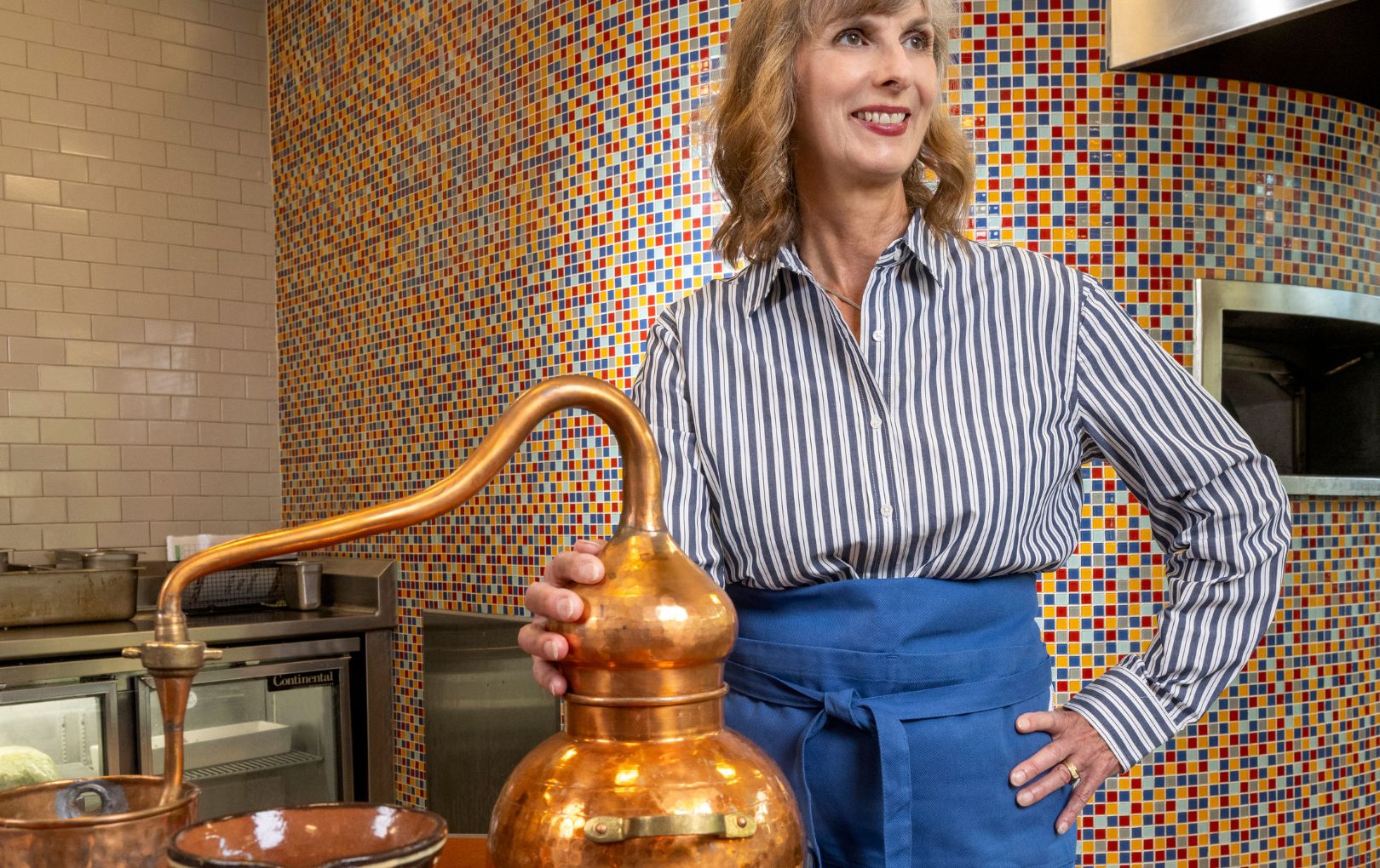 Amy Tigner stands with a copper still used to make chocolate and a traditional chocolate pot