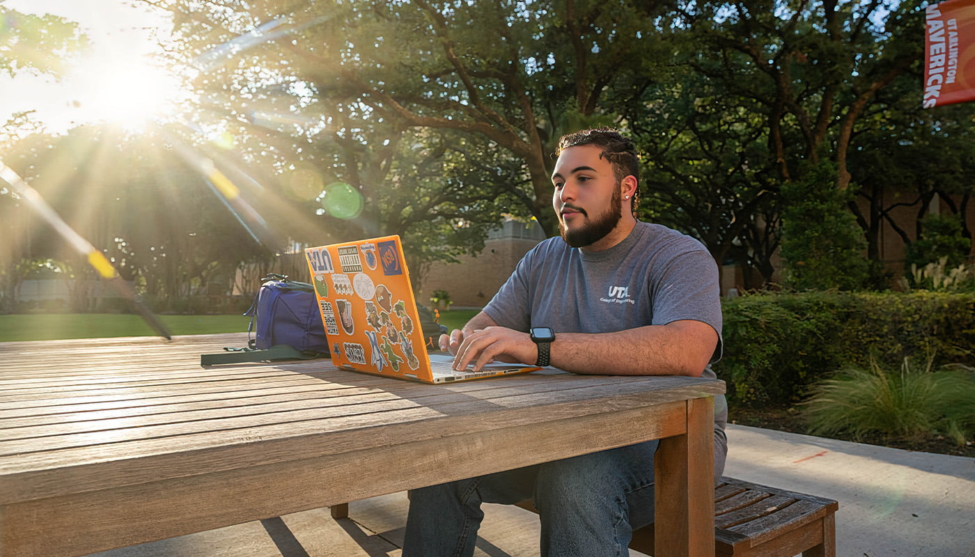 a man working on a laptop at a picnic table