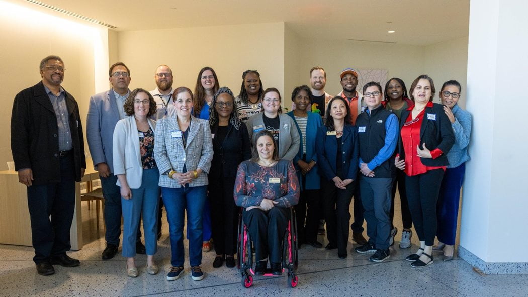 group of peopl standing together with one person sitting in wheelchair