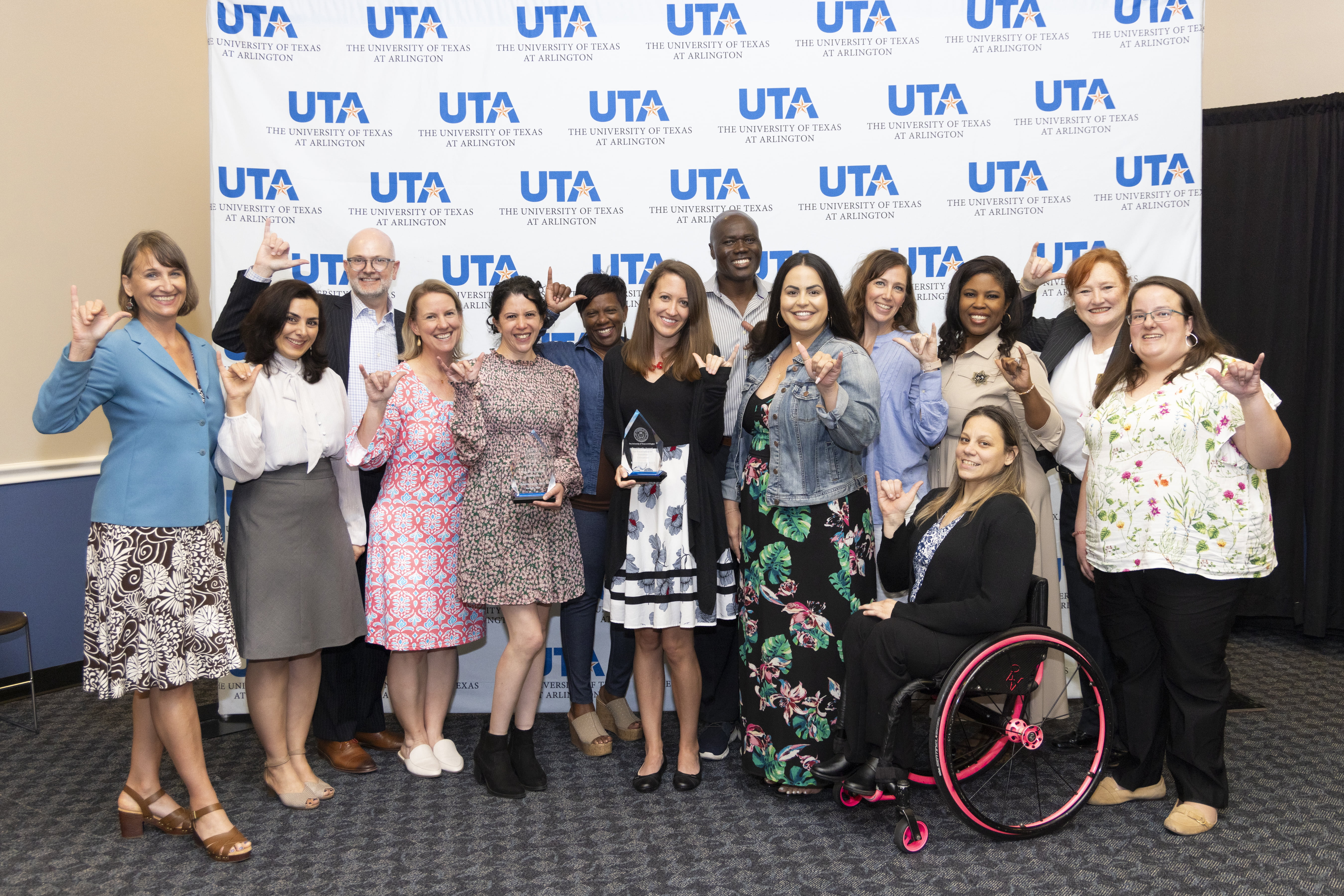group of people standing in front of UTA backdrop