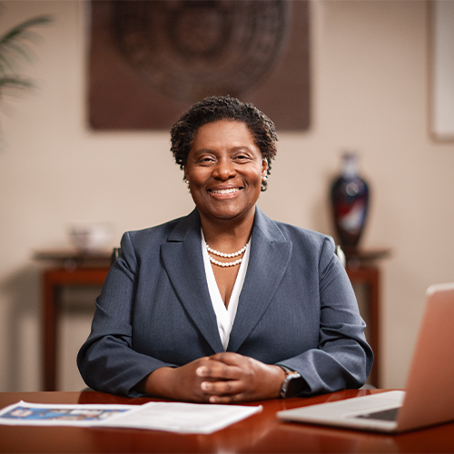 Provost Tamera Brown Sitting at a desk grinning gleefully