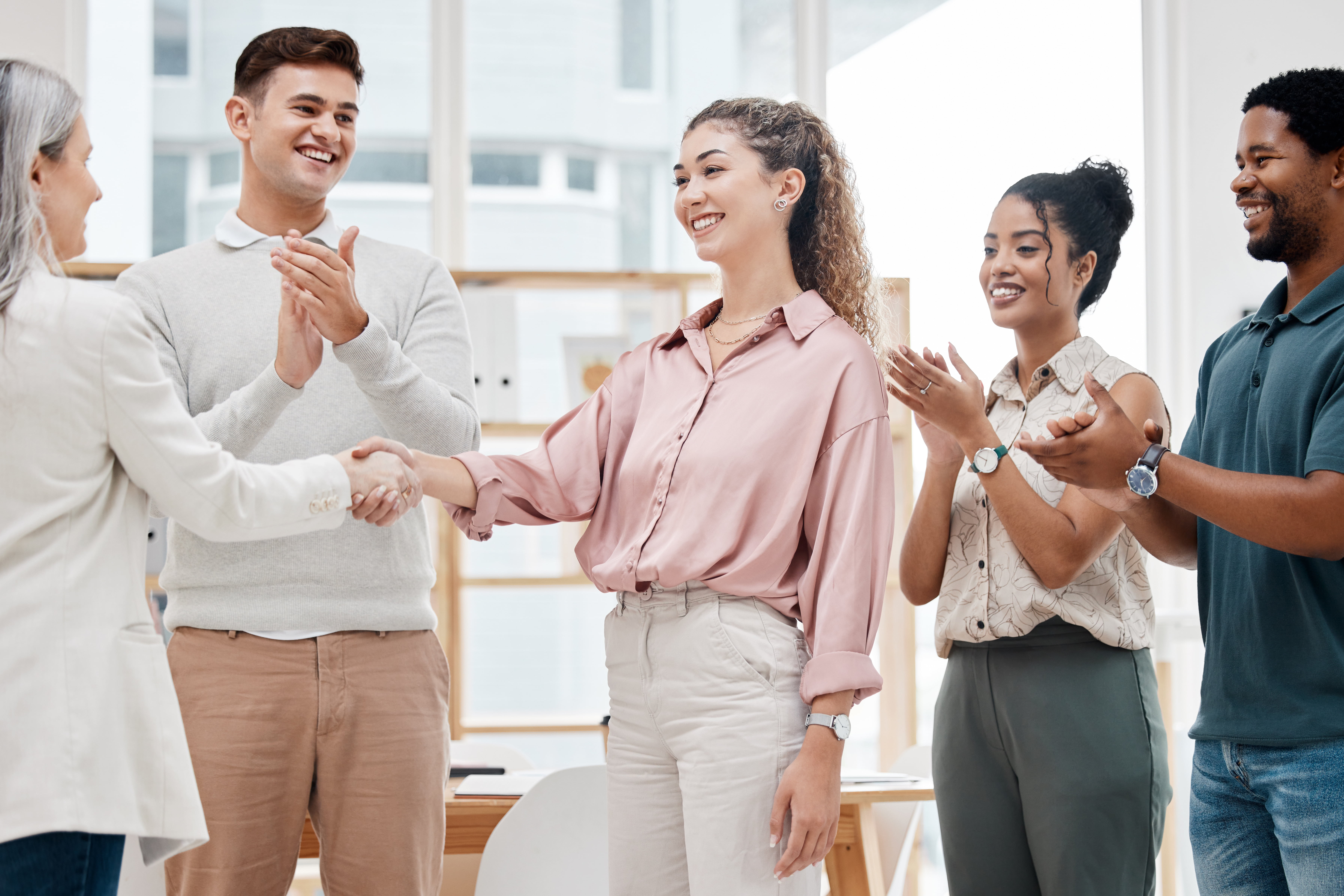 A group of people welcoming another person through a hand shake. 