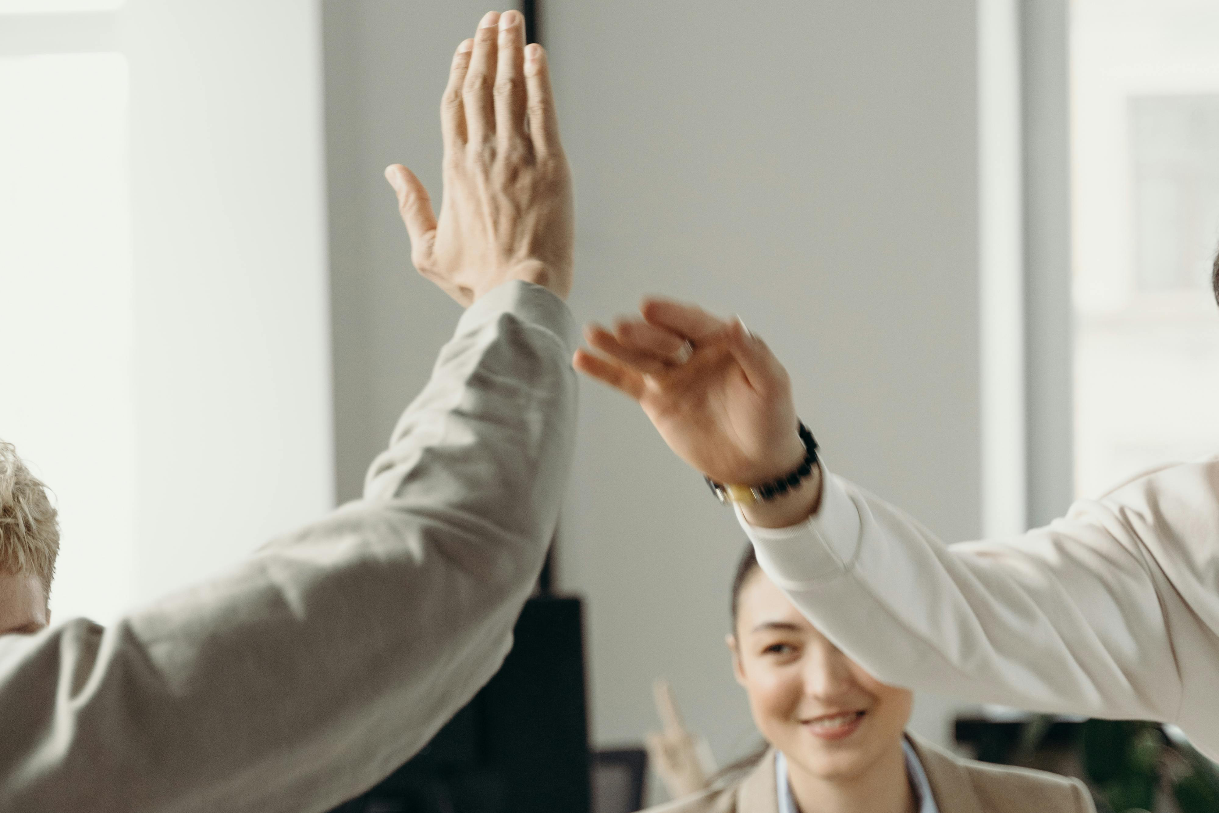 two hands giving a a high five, and some people around celebrating. 