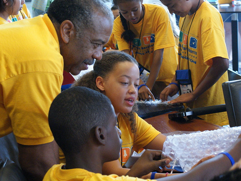 School children work through an experiment with an advisor at summer camp.