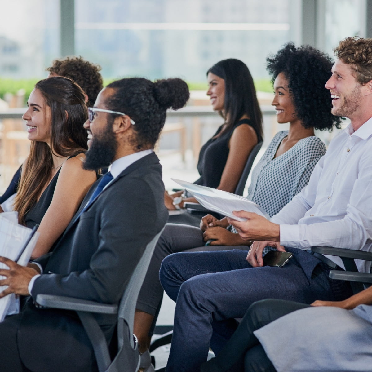 A diverse group of students and professionals laughing and engaged during a university presentation.