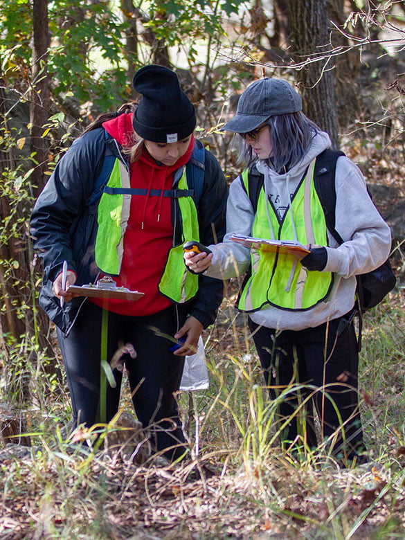 Two students survey a compass at Field Camp.