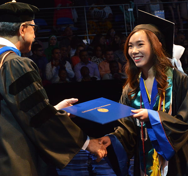 A female student receiving her degree from College of Science Dean Morteza Khaledi during commencement ceremony.