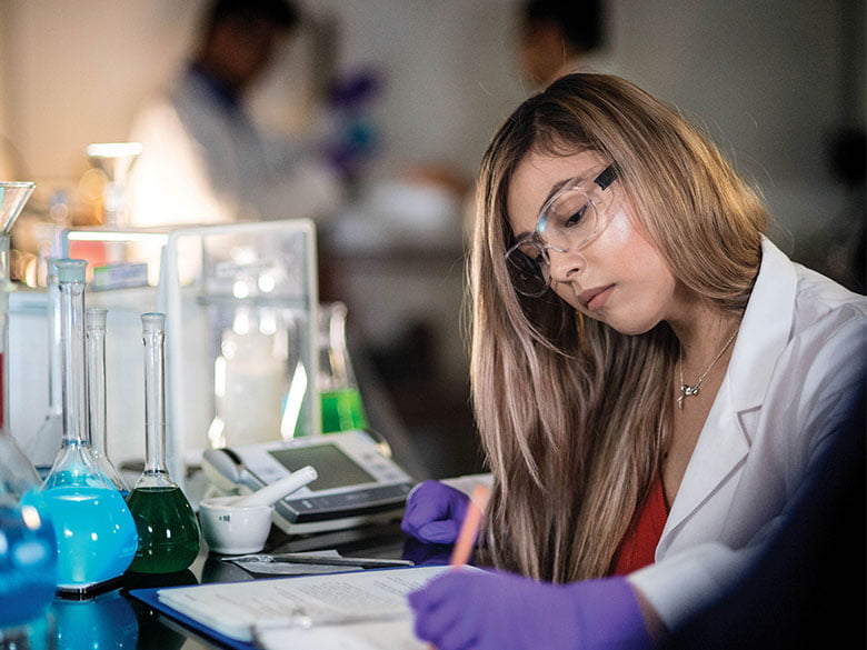 A chemistry student writes notes in the lab. 