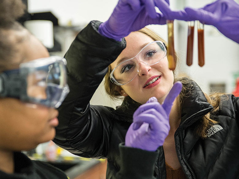 Two students investigate a trio of beakers in the lab. 