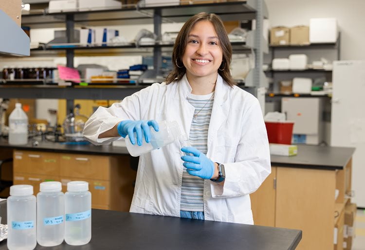 Isabella Rios, wearing a white lab coat, working in a lab