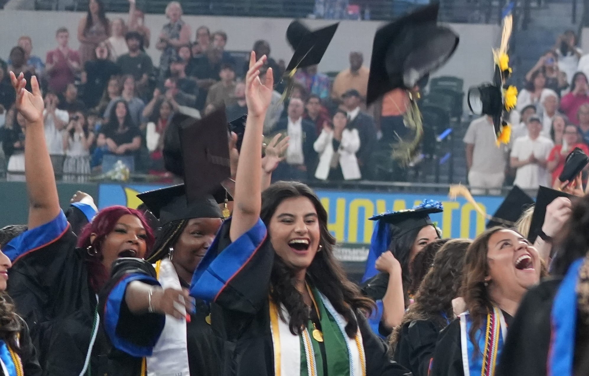 U T A graduate students throw their caps in the air after graduation.