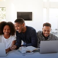 An adult working with children on laptop