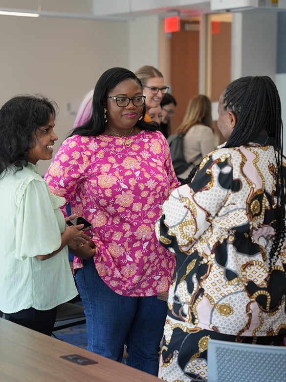 Three students talking with each other during the School of Social Work PostDoc Research Day.