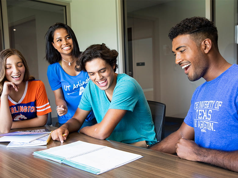 UTA students sitting at a table having a group discussion.