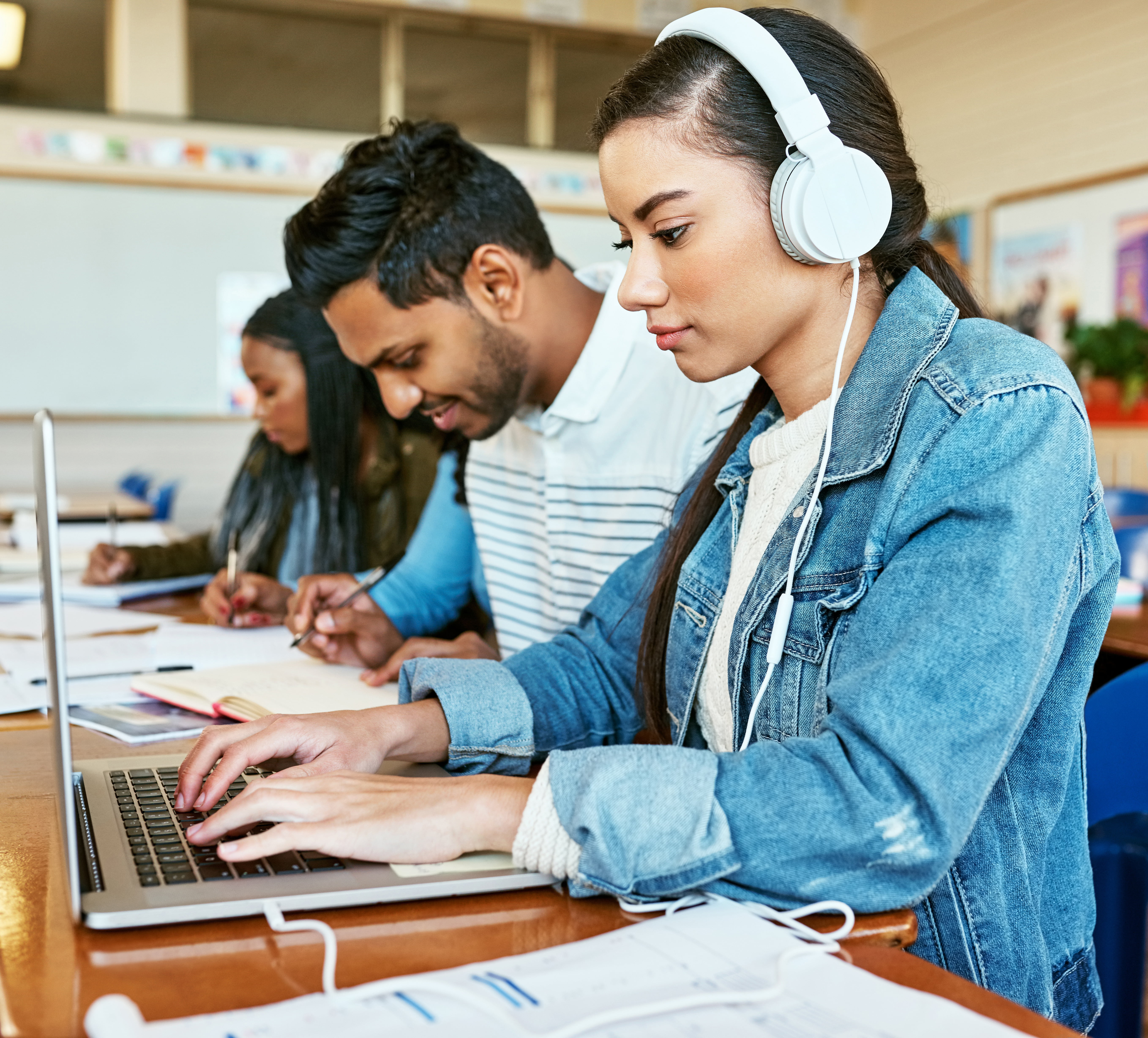 Students sitting at a desk with their laptops.