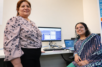 Two School of Social Work PhD students in front of a computer during a research event.