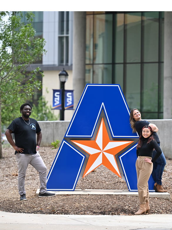 UTA students standing next to UTA signage outside