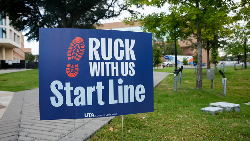 A sign posted in the ground that say Ruck With Us - Start Line