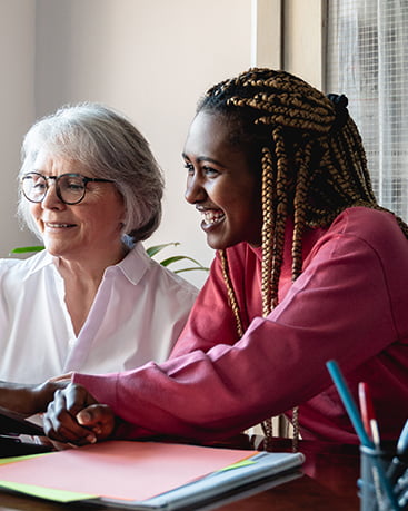 A person helping an elderly person on a laptop.