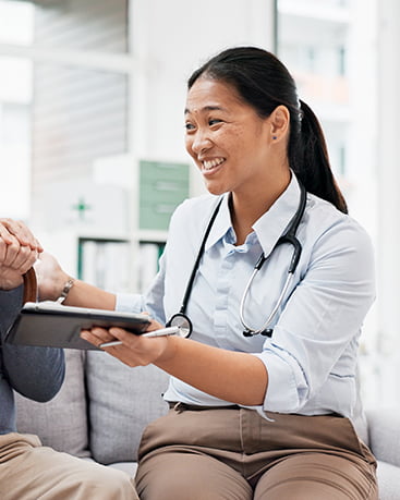 A doctor with a stethoscope around her neck speaking with a patient.