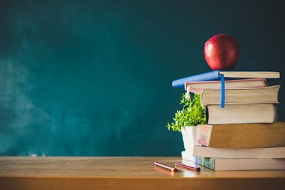 Books on desk with a apple on top