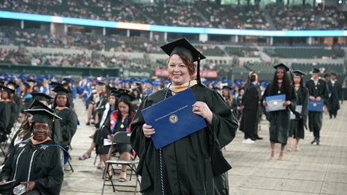 UTA graduate walking down aisle during Spring 2025 Commencement