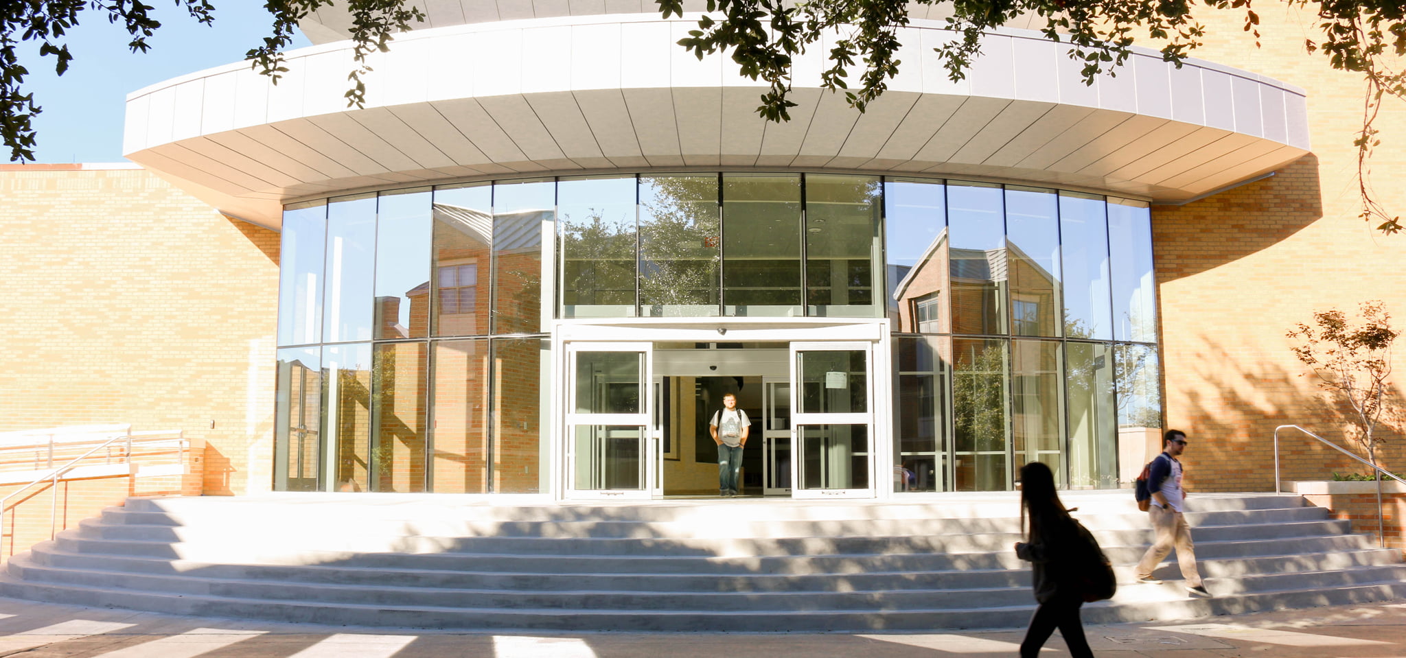Front entrance of a building with a student coming out of it.