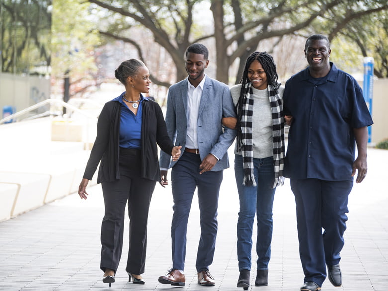 Family of four walking on campus and smiling