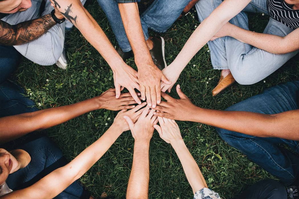 Hands placed on top of one another in the center in a bonding experience.