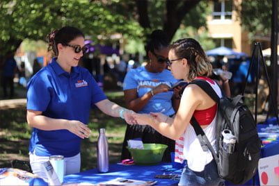 Staff handing items from a table to a student