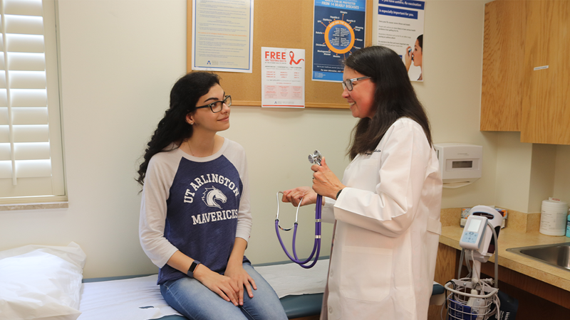 UTA docotr performing clinical exam on student